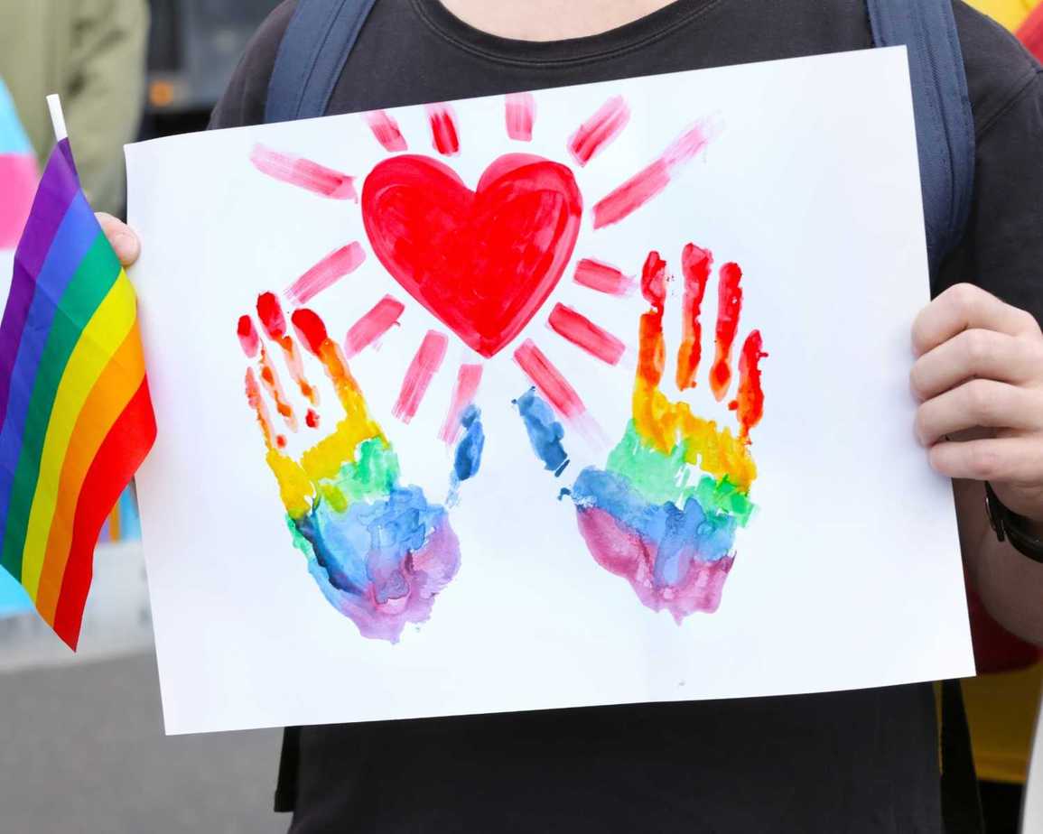 Person Holding a Poster and Flag for the LGBTQ Community